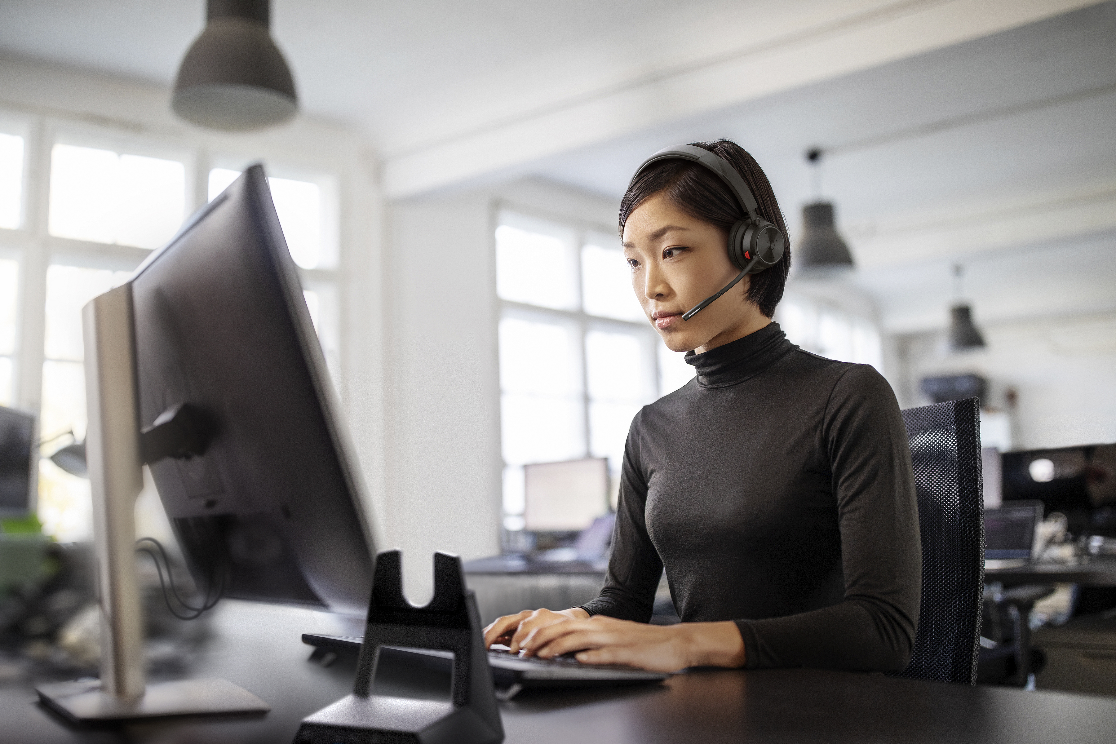 Woman working at her desk in open plan office with Savi 7300 Office Series